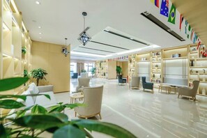 A hotel lobby with seating areas, a reception desk, and a large window.