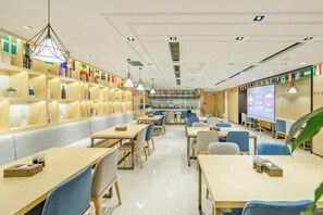 A modern library with bookshelves, tables, chairs, and a projection screen. - Saint Hotel (Chongqing)