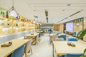 Una biblioteca moderna con filas de mesas y sillas, estanterías y una pantalla grande para presentaciones.