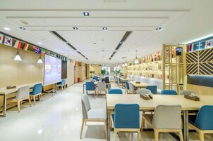 Un moderno salón de conferencias con mesas, sillas, una pantalla de proyección y una estantería.