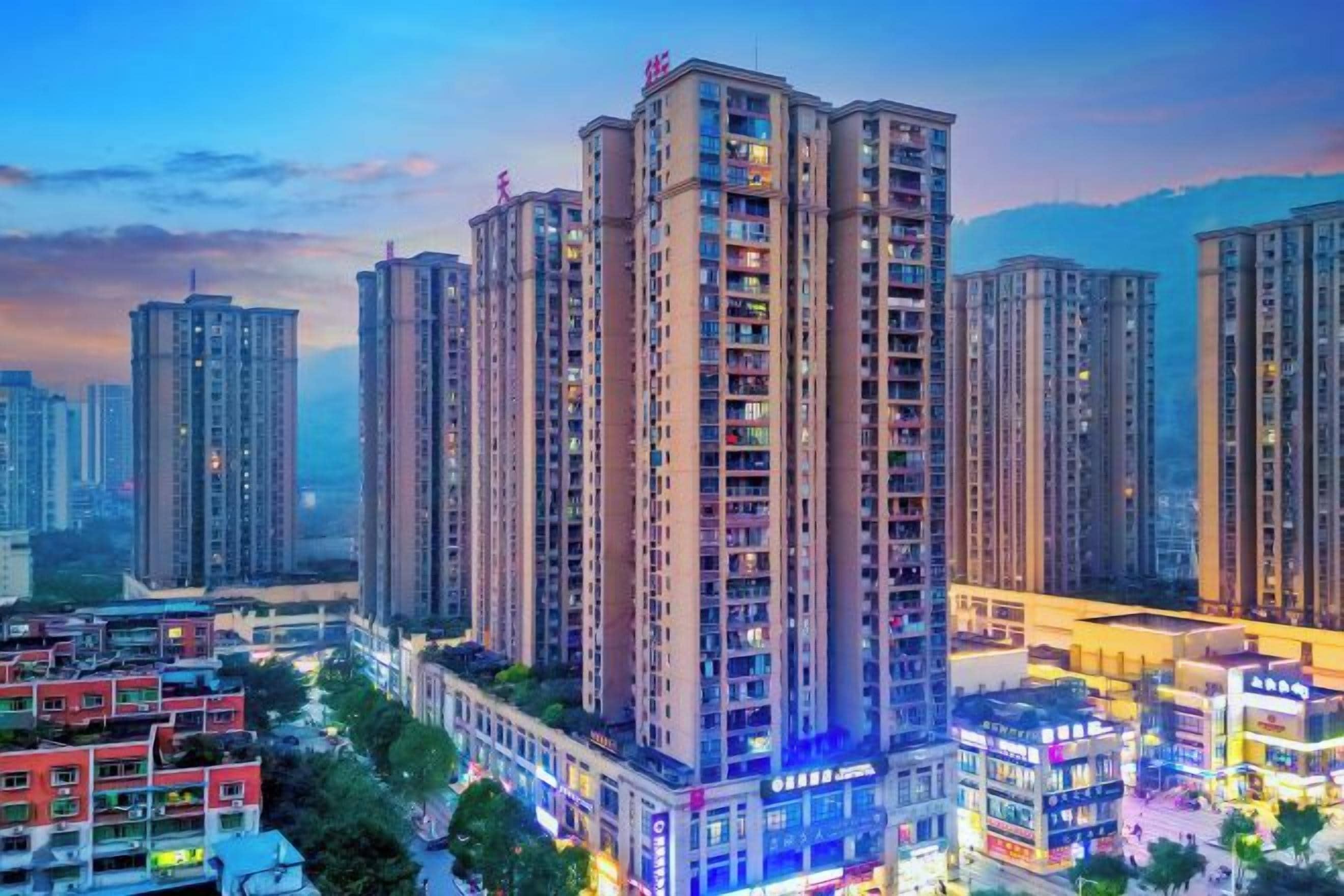 A high-rise residential building with multiple floors, surrounded by other high-rise buildings, and a busy street with commercial establishments.