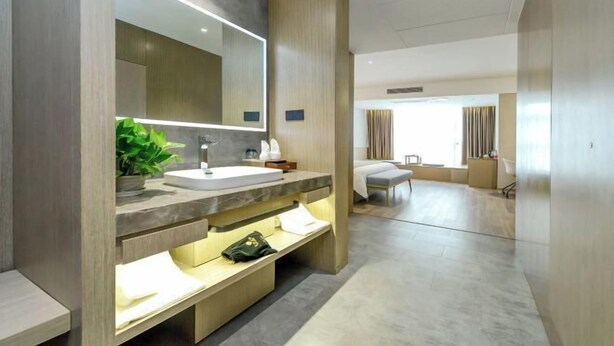 A modern bathroom with a large mirror, a sink, and a bench. - Saint Hotel (Chongqing)