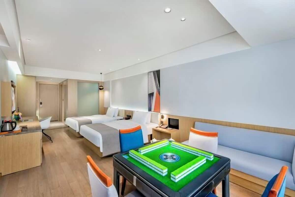 A modern hotel room with a bed, a desk, a sofa, and a pool table.