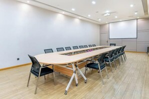 A conference room with a long table, chairs, a projector screen, and a whiteboard.