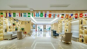 A hotel lobby with a central seating area, bookshelves on either side, and a ceiling with hanging flags. - Saint Hotel (Chongqing)