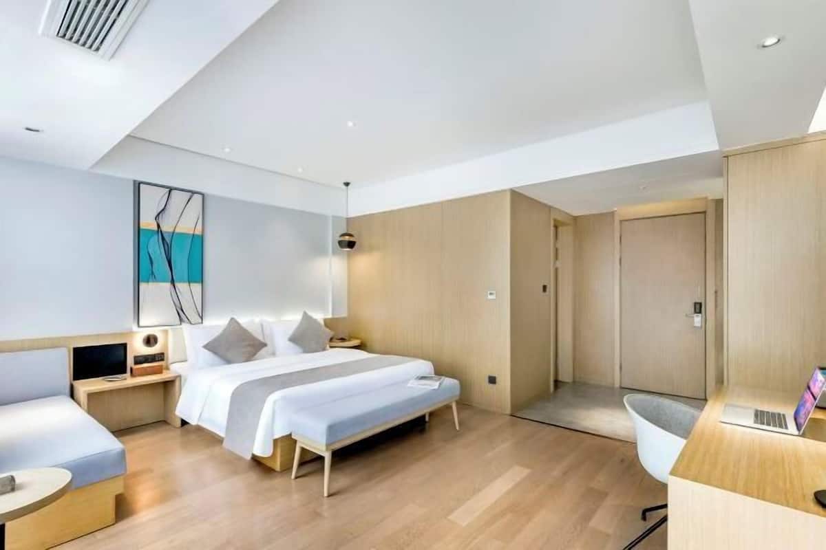 A modern hotel room with a bed, bedside tables, a desk, and a chair.