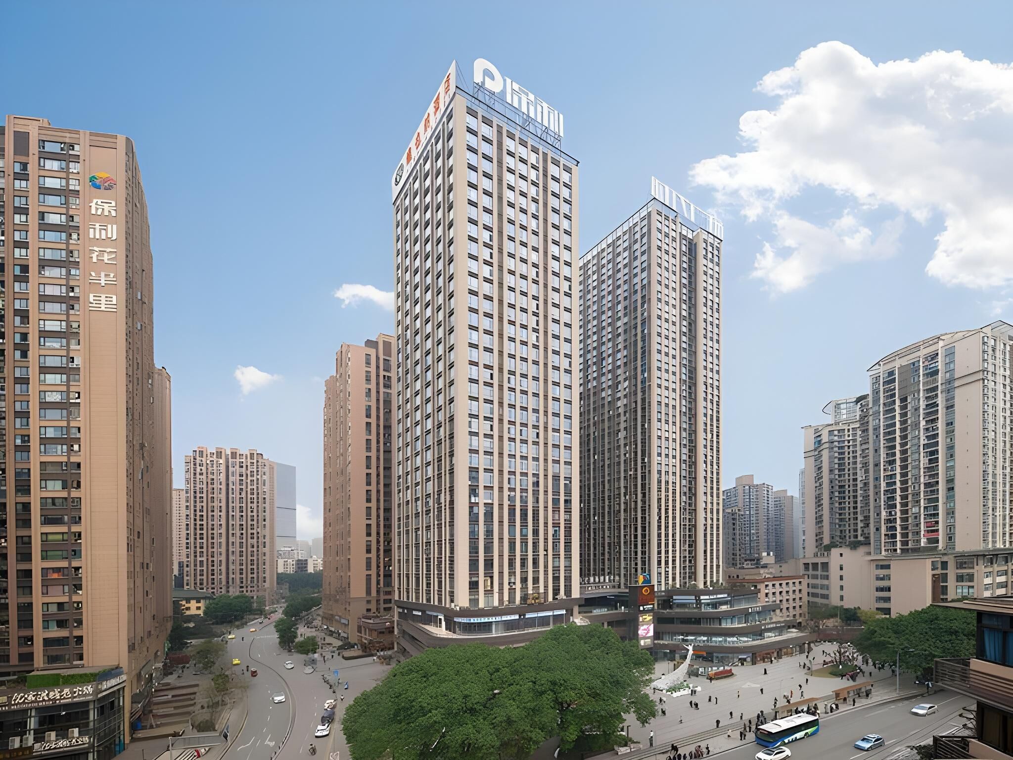 A high-rise building with multiple floors, a prominent sign at the top, and a surrounding urban environment with other buildings and a clear sky.