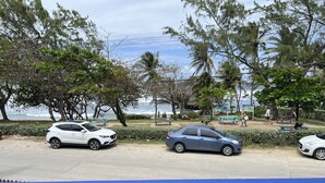 A coastal road with parked cars, a bench, and a view of the ocean. - Surfs Up - bungalow style Beachhouse opposite Atlantic Ocean (Bathsheba)