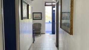 A hallway with tiled flooring, framed artwork on the walls, and a bench. - Surfs Up - bungalow style Beachhouse opposite Atlantic Ocean (Bathsheba)