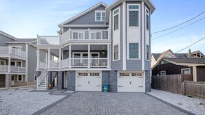 A two-story house with a balcony, a garage, and a stone pillar. - Stunning Point Pleasant Beach 6BR 5Bath Ocean Front Home - Heated Inground Pool (Point Pleasant Beach)