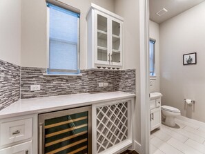 Un baño con salpicadero de azulejos, inodoro y lavabo con armario superior.