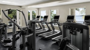 Un gimnasio con cintas de correr, máquinas de pesas y equipamiento de ejercicio.