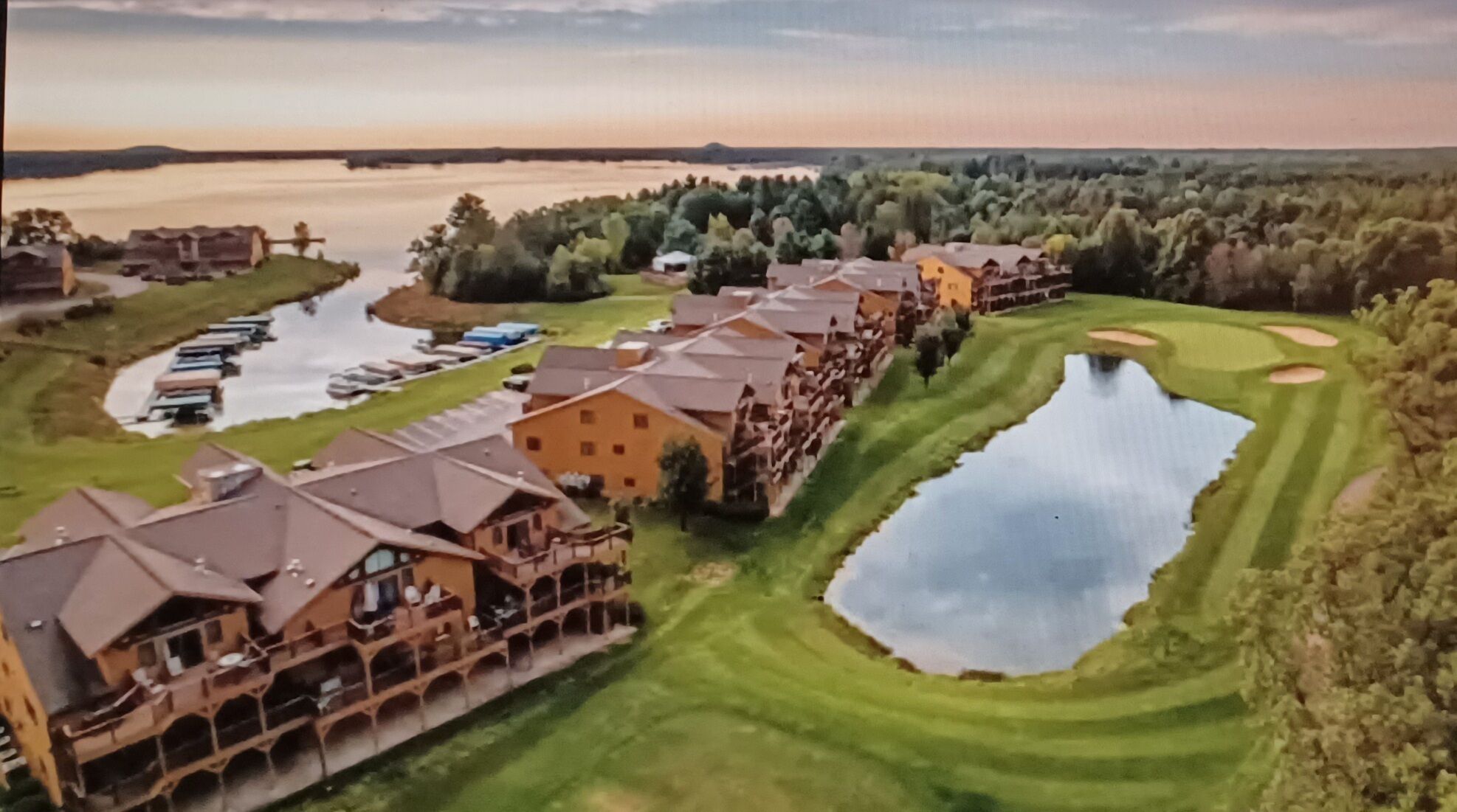 A resort with multiple buildings, a golf course, and a lake.
