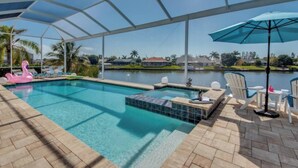 A covered outdoor swimming pool with lounge chairs and a hot tub. - Villa Blissful Bay - The Entry To Paradise (Cape Coral)