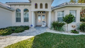 A two-story house with a central entrance, a covered patio, and a well-maintained garden. - Villa Blissful Bay - The Entry To Paradise (Cape Coral)