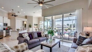 A spacious living room with a sofa, coffee table, and a view of a pool and outdoor area. - Villa Blissful Bay - The Entry To Paradise (Cape Coral)