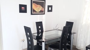 A dining area with a glass table, black chairs, and a framed picture on the wall. - Céntrico Próximo Clínica Unión Médica (Santiago de los Caballeros)