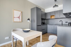 A modern kitchen with grey cabinets, a white dining table, and a bowl on it.