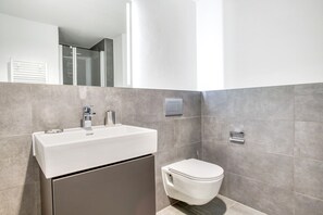 Un baño moderno con un lavabo blanco, un inodoro y un espejo.