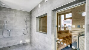 A modern bathroom with grey tiles, a glass shower enclosure, and a wooden bench. - Deluxe Leopoldstadt 2BR w/ Loggia, Gym & Sauna, near U2, by Blueground (Vienna)