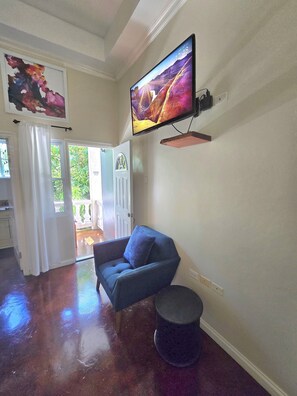 A living room with a flat-screen TV mounted on the wall, a blue sofa, and a small round table.