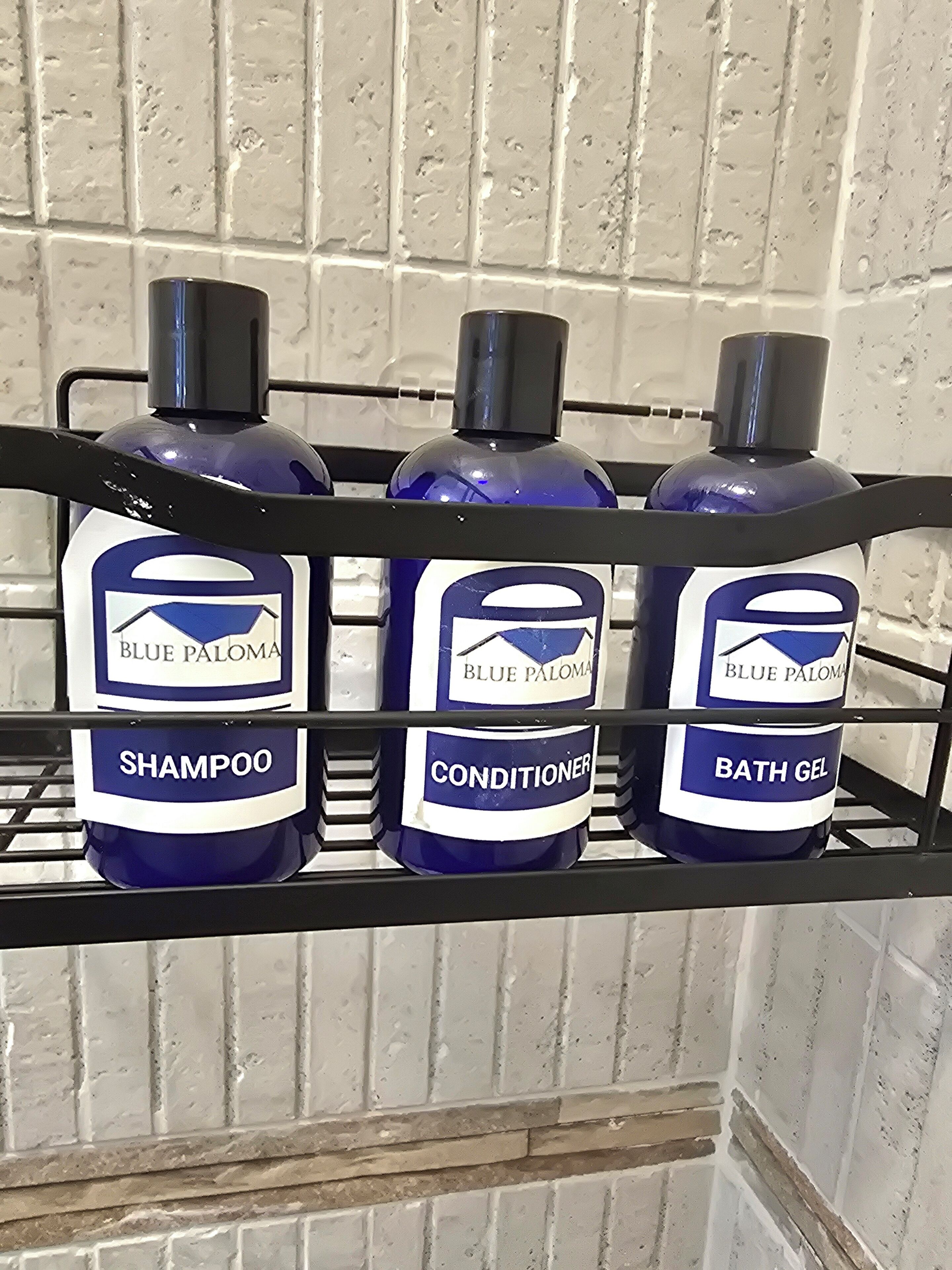 Três garrafas de produtos Blue Paloma sobre uma prateleira de metal.