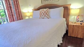 Una cama bien hecha con una colcha estampada, un cabecero de madera y dos lámparas de noche.