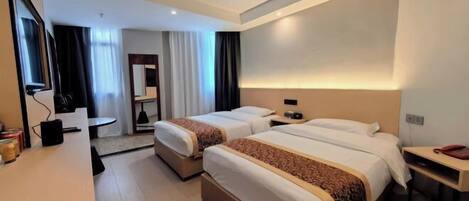 A hotel room with two beds, a desk, a chair, a TV, and a mirror.