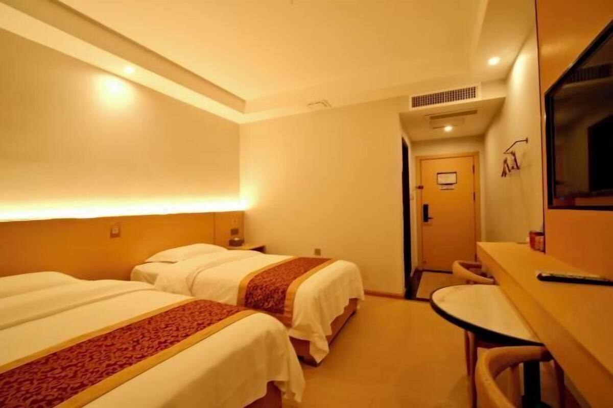 Ein Hotelzimmer mit zwei Betten, einem kleinen Schreibtisch und einem Spiegel.
