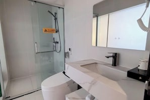 Un baño moderno con cabina de ducha de vidrio, inodoro blanco, lavabo de mármol y espejo sobre el lavabo.