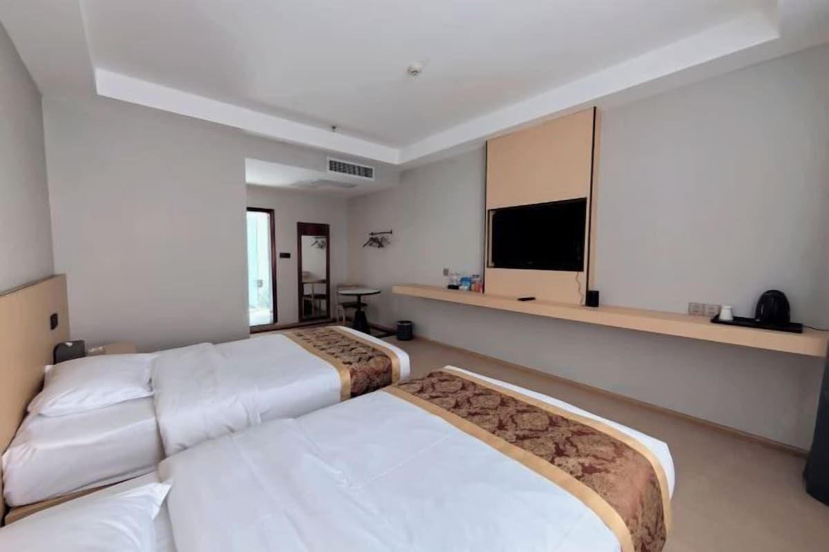 Habitación de hotel con dos camas, televisión, una mesita y un escritorio.