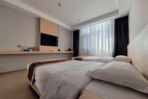 A hotel room with a bed, a TV mounted on the wall, a window with curtains, and a shelf with toiletries. - Zhijin Shancheng Hotel (Zhijin)