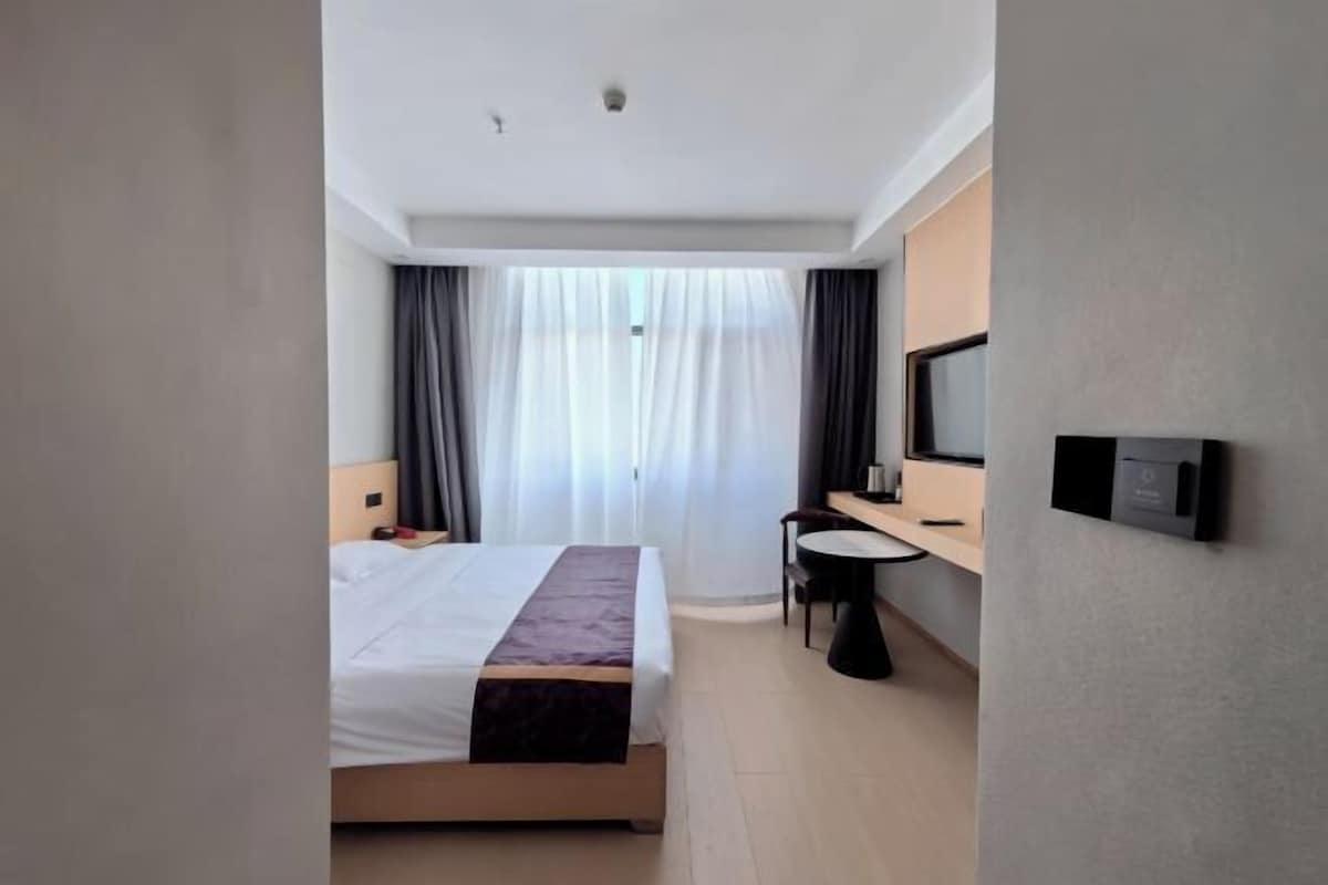 Una habitación de hotel moderna con una cama, un escritorio, una silla y un televisor.