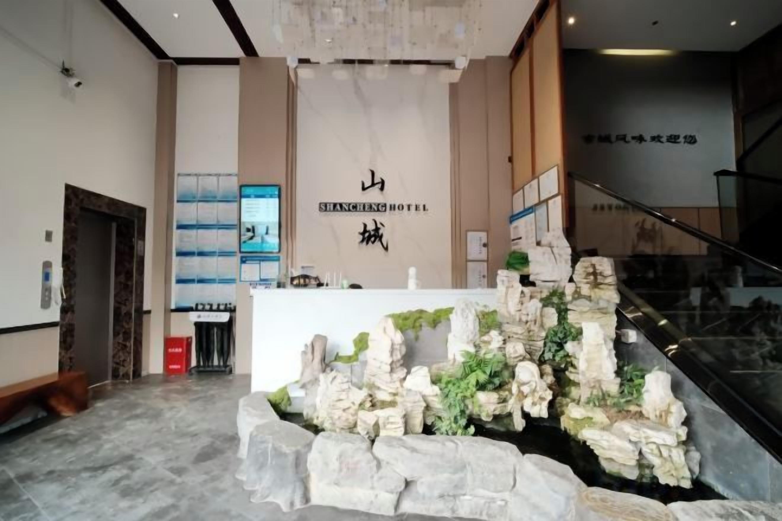 A reception area with a stone waterfall feature, a reception desk, and a staircase leading to an upper level.
