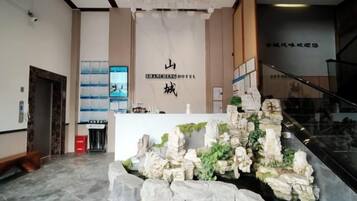 A reception area with a stone waterfall feature, a reception desk, and a staircase leading to an upper level.