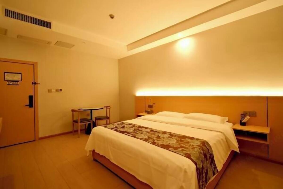 Ein Hotelzimmer mit Bett, Nachttisch, Stuhl und kleinem Tisch.