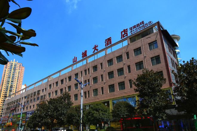 A multi-story hotel with a prominent sign, surrounded by trees and a clear sky.