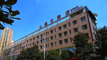 A multi-story hotel with a prominent sign, surrounded by trees and a clear sky.