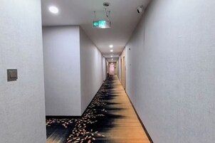 Un largo pasillo estrecho con suelo alfombrado y un proyector en el techo.