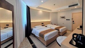 A hotel room with two beds, a desk, a coffee maker, and a mirror. - Zhijin Shancheng Hotel (Zhijin)