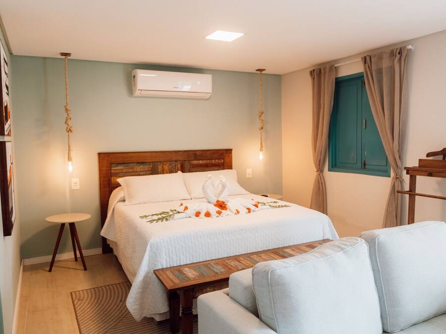A bedroom with two beds, a sofa, a wooden table, and a hanging light fixture.