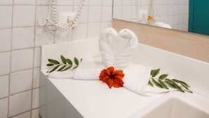 A bathroom with white tiles, a white sink, and two hair dryers mounted on the wall. - Catamaran Praia Chalés (Igarassu)