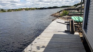A wooden dock extending into a calm body of water, with a green lounge chair and a wooden bench on the right side. - Fabulous New Georgian Bay Cottage on the  water! (Byng Inlet)