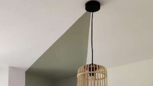 Una stanza con una poltrona d'angolo, un letto e una lampada a sospensione.