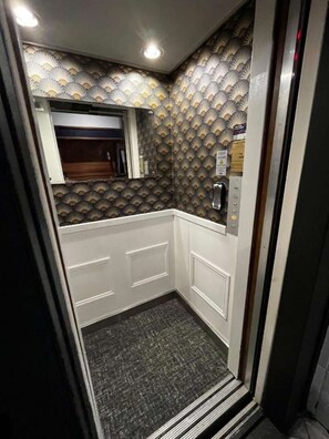 Modern bathroom with a geometric patterned wallpaper and a compact design featuring a sink, mirror, and faucet.