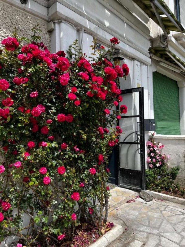 Stunning stone facade with a traditional entrance, surrounded by lush greenery and a vibrant flowering bush.