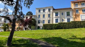 Un immeuble résidentiel doté d’une cour intérieure, entouré de verdure et surplombé d’un ciel dégagé.