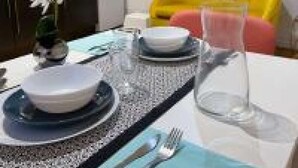 Une table à manger dressée avec des assiettes, des couverts et un verre.