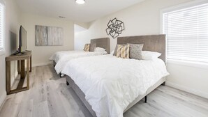 A bedroom with two beds, a TV on a stand, and a modern abstract art piece on the wall. - Modern clean relaxing gateway! Close to all LA fun! (Monterey Park)