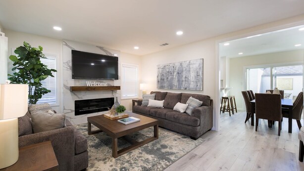 A modern living room with a fireplace, a television, and a dining area with chairs and a table. - Modern clean relaxing gateway! Close to all LA fun! (Monterey Park)
